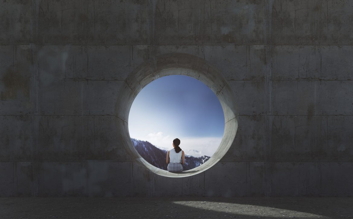 Lonely young woman sitting and looking through concrete window