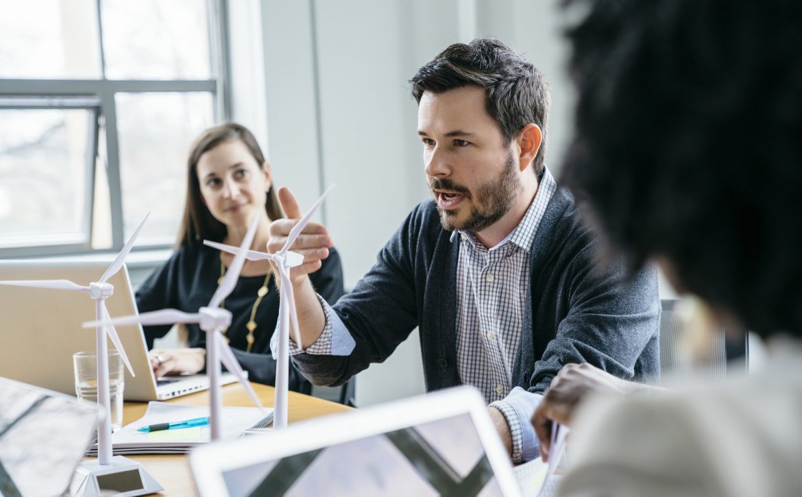 Businessman explaining wind turbine models to colleagues in office