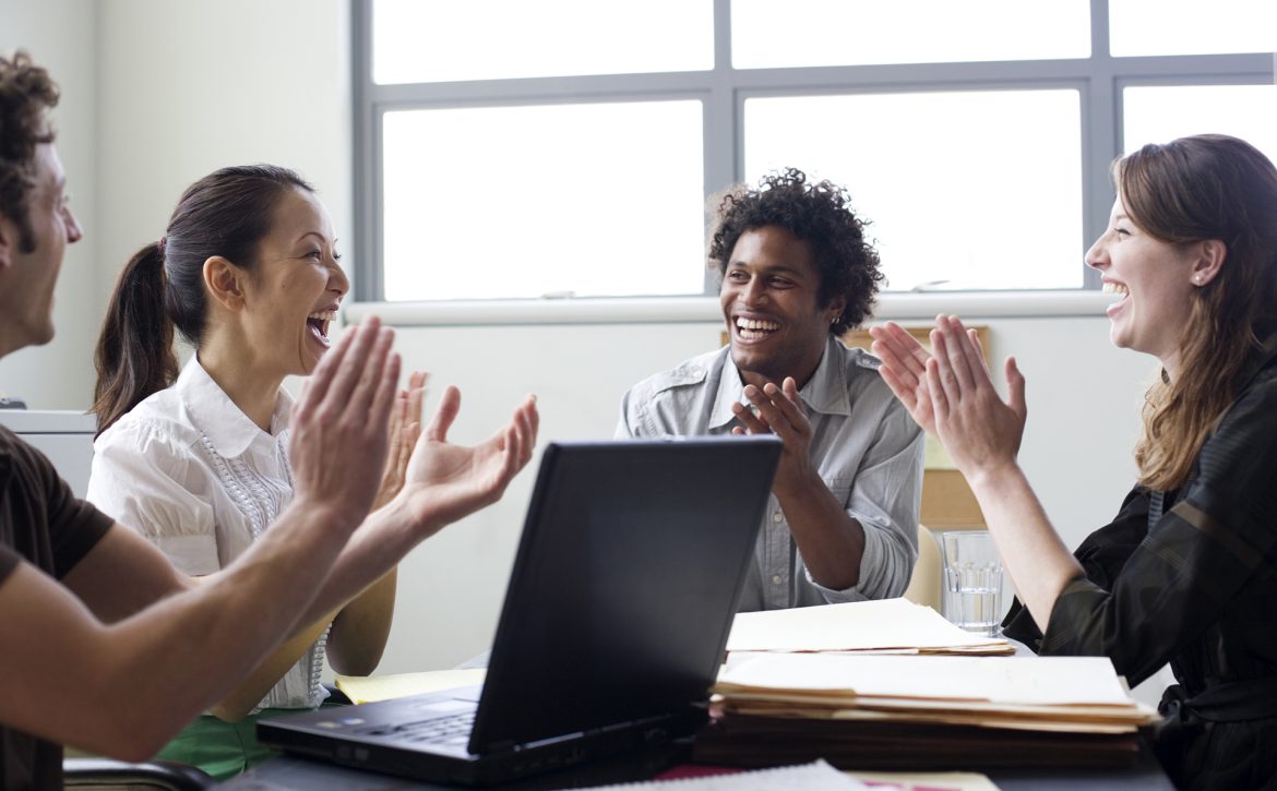 Four businesspeople in office applauding