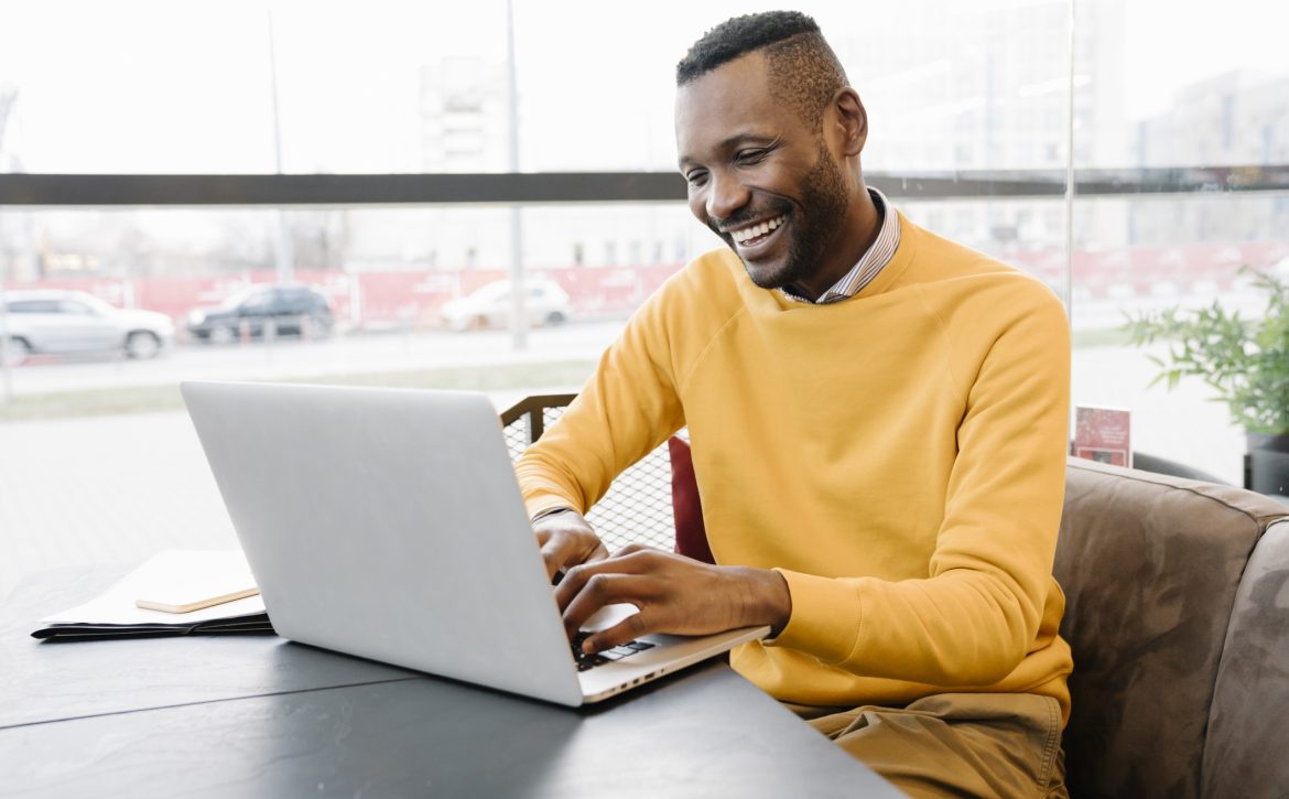 Happy man using laptop in a cafe