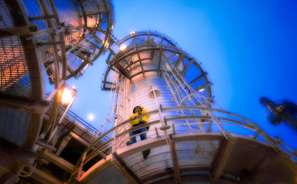 Man on oil refinery distillation tower